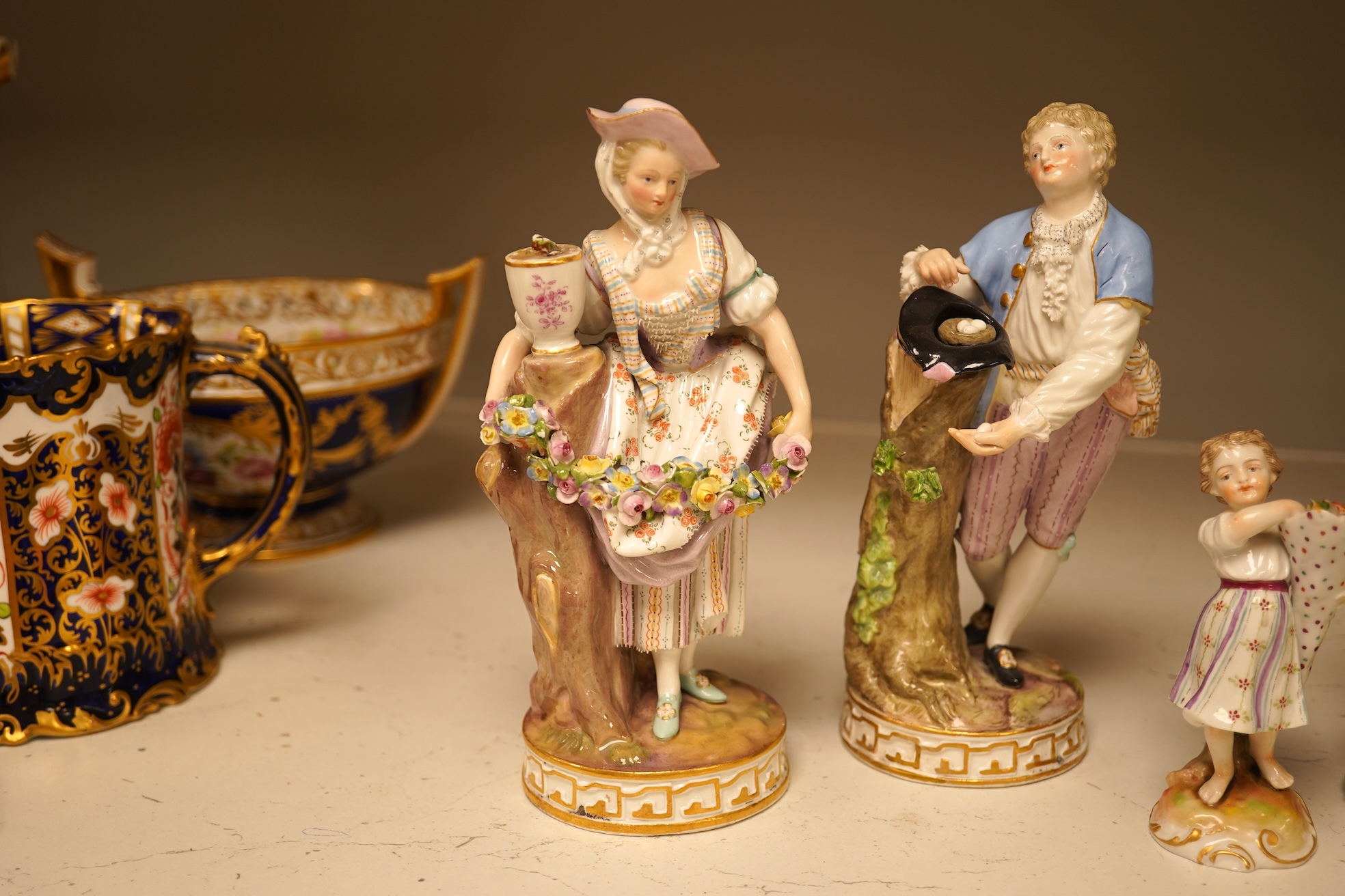 A pair of 19th century Meissen figurines, a Crown Derby figure, a pair of miniature figures and a Leeds type creamware group of Venus and Cupid, tallest 18cm high.